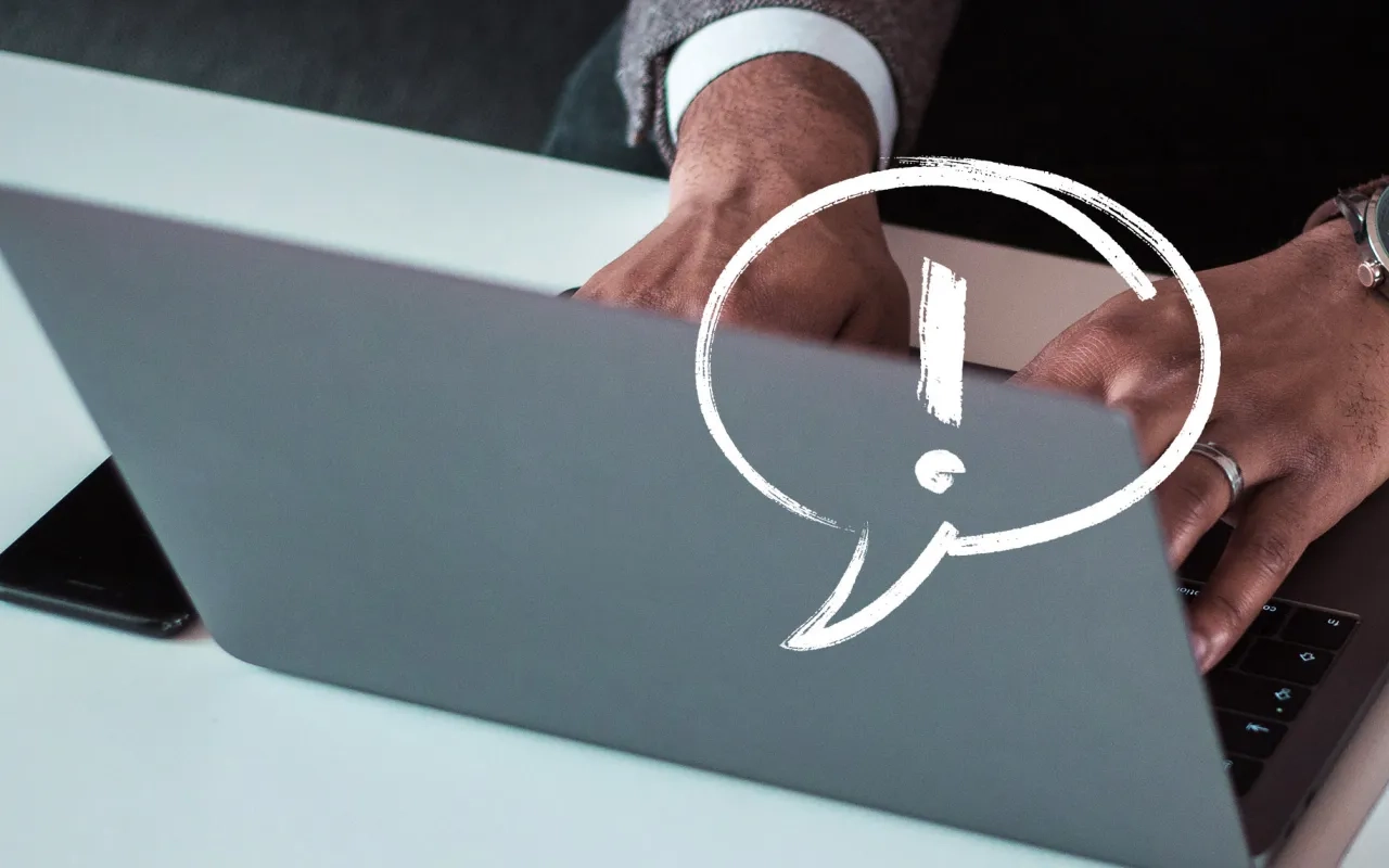 Hands typing on a laptop, with an exclamation bubble graphic.