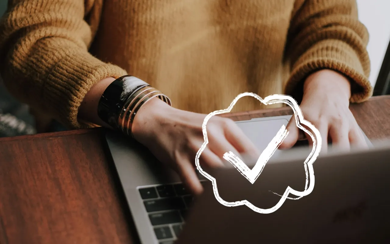 Hands typing on a laptop, with a checkmark graphic overlay.